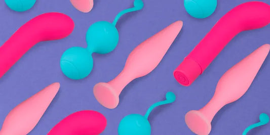 Diferentes juguetes sexuales de silicona en colores rosa y azul sobre fondo morado, incluyendo vibradores, plugs anales y bolas chinas para fortalecer el suelo pélvico.