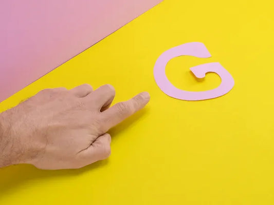 Mano señalando una letra 'G' sobre fondo amarillo, simbolizando la búsqueda y estimulación del punto G en la exploración sexual femenina.