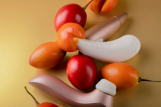 Succionador con vibración en tonos dorados junto a frutas exóticas, simbolizando placer intenso y estimulación sin fricción.